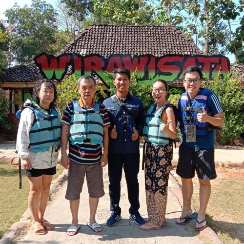 a group of people standing in front of a sign at Rumah Ukhi Guest House in Yogyakarta