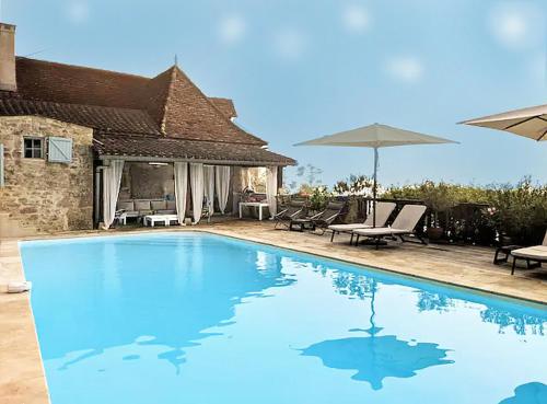 - une piscine avec un parasol et une maison dans l'établissement Relaxen bij zwembad met zicht over de Célé vallei, à Sauliac-sur-Célé