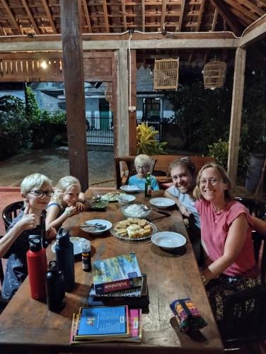 a group of people sitting around a wooden table at Rumah Ukhi Guest House in Yogyakarta