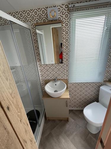 a bathroom with a sink and a toilet and a mirror at 6 birth caravan chapel st Leonards trunch lane in Chapel Saint Leonards