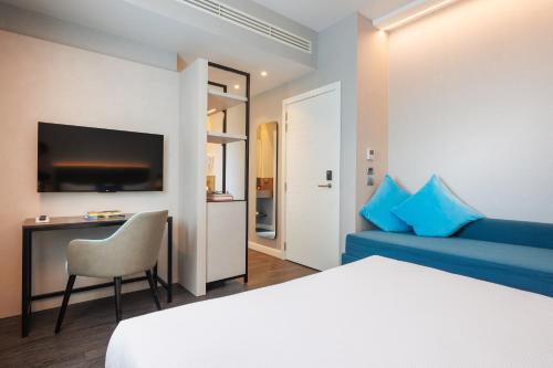 a hotel room with a bed and a blue couch at IH Hotels Milano Centrale in Milan