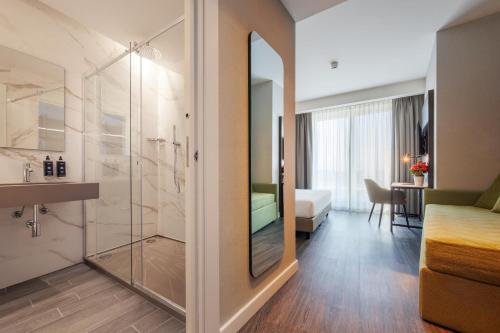 IH Hotels Milano Centrale في ميلانو: غرفة في الفندق مع دش وغرفة نوم