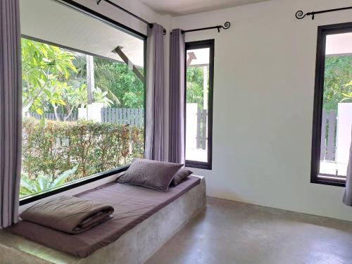a bed in a room with large windows at Magic House - No Pets Allowed in Chumphon