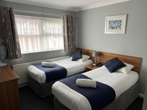 a hotel room with two beds and a window at Corner House Hotel Gatwick with bookable Holiday parking in Horley