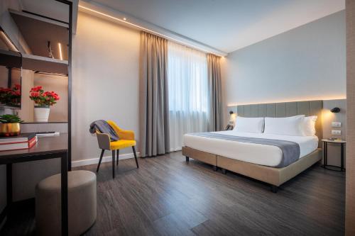 a hotel room with a bed and a desk at IH Hotels Milano Centrale in Milan