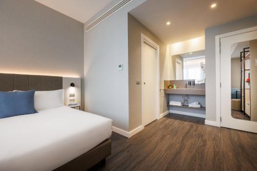 a bedroom with a white bed and a bathroom at IH Hotels Milano Centrale in Milan