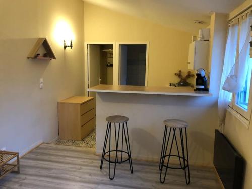 uma cozinha com dois bancos de bar e um balcão em Charmant studio proche centre ville d’Orléans em Orléans