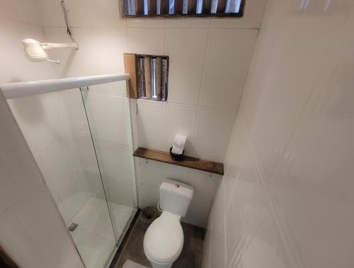 a small bathroom with a toilet and a window at Pousada Raiz Forte in Caraíva