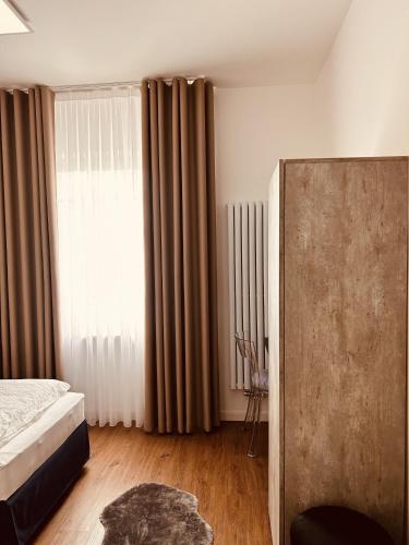 a bedroom with a bed and a window with curtains at Pension und Location Cham in Meerbusch