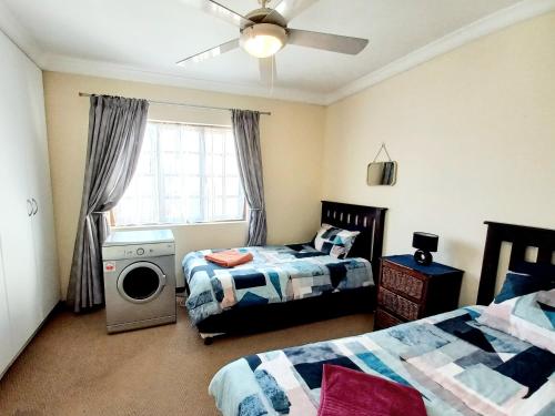 a bedroom with two beds and a washing machine at 57 Settler Sands Beach Apartment in Port Alfred