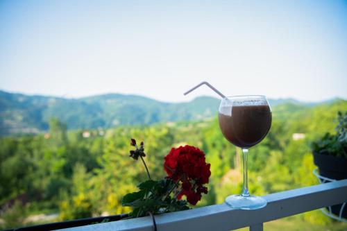 a glass of wine sitting on a railing with a flower at Zelinjski vidikovac in Zvornik