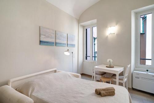 - une chambre blanche avec un lit et une table dans l'établissement Casa Elena, à Bordighera