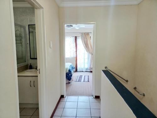 a bathroom with a sink and a door to a bedroom at 57 Settler Sands Beach Apartment in Port Alfred