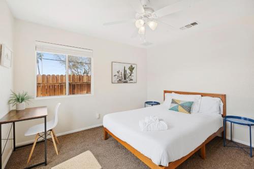 Schlafzimmer mit einem Bett, einem Schreibtisch und einem Fenster in der Unterkunft Cassia Tree in Twentynine Palms