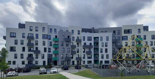 un grand bâtiment blanc avec des voitures garées dans un parking dans l'établissement APARTAMENT OLIWIER, à Kłodzko