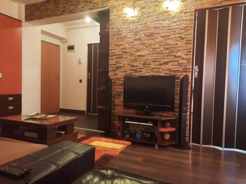 a living room with a television and a brick wall at Apartament cu parcare privata in Arad