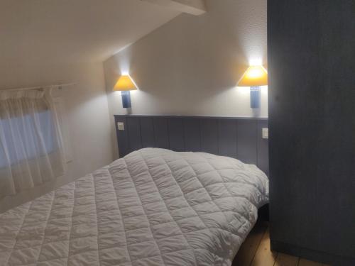 a bedroom with a bed with two lights on the wall at Olydea Oleron les Sables Vignier in Saint-Georges-dʼOléron