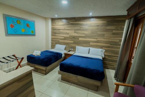 a bedroom with two beds and a wooden wall at Hotel Santiago De Compostela - Guadalajara Centro Historico in Guadalajara