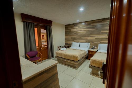 a hotel room with two beds and a chair at Hotel Santiago De Compostela - Guadalajara Centro Historico in Guadalajara