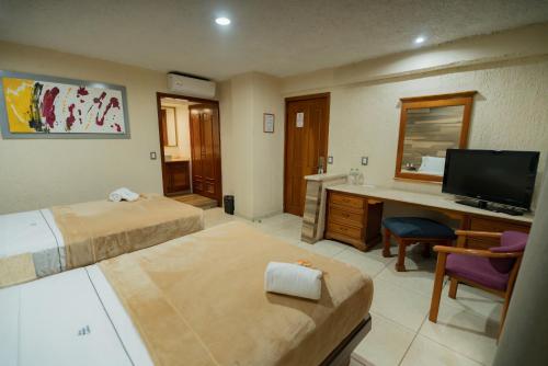 a hotel room with two beds and a desk with a television at Hotel Santiago De Compostela - Guadalajara Centro Historico in Guadalajara