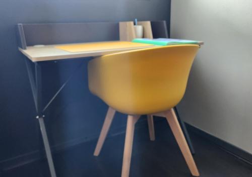 a desk with a yellow chair in a room at 'Les Tropiques' - Parking privé - Balcon - Tout confort in Joué-lès-Tours