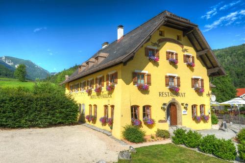 um edifício amarelo com caixas de flores em DEVA Hotel Alpenglück em Weißbach