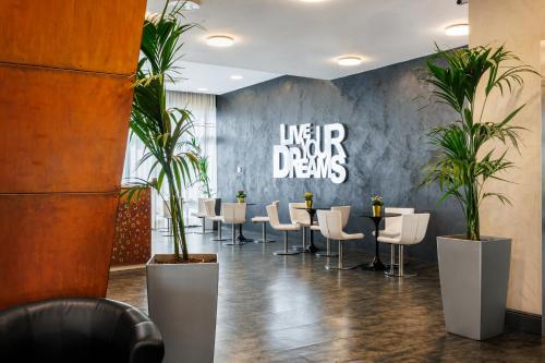 a restaurant with a long table and chairs and plants at iH Hotels Milano Lorenteggio in Milan