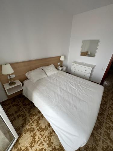 1 dormitorio con 1 cama blanca grande y espejo en El Popet de Baix a Mar, en Torredembarra
