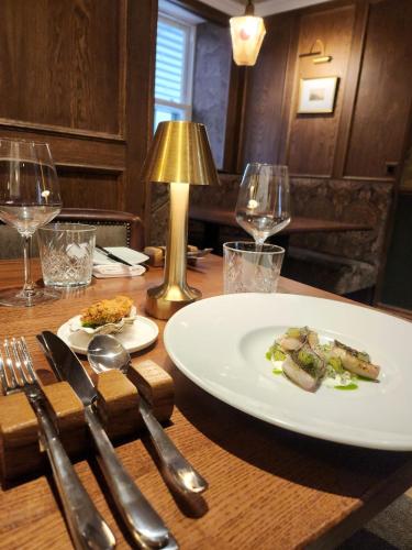 a wooden table with a plate of food and wine glasses at The Fanny Talbot in Barmouth