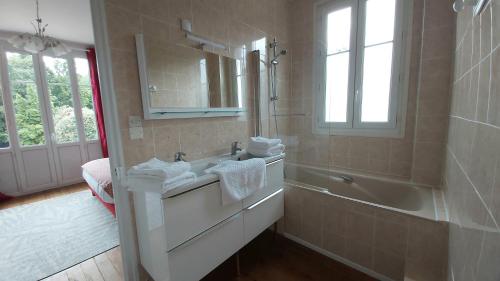 een badkamer met een wastafel, een bad en een spiegel bij La Villa des Tilleuls in Cambremer