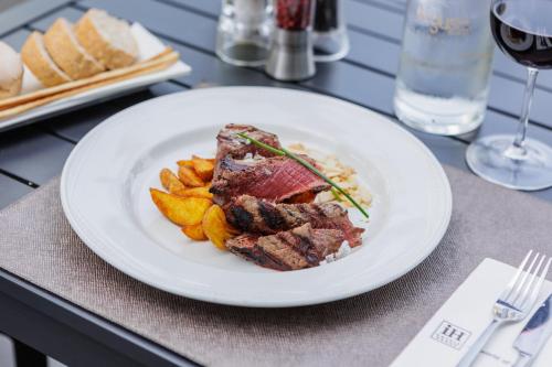 a plate of food with meat and fries on a table at iH Hotels Milano Lorenteggio in Milan