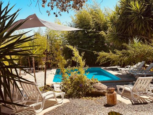 a swimming pool with two lawn chairs and an umbrella at Casa Rico Frade Garden in São Pedro do Corval