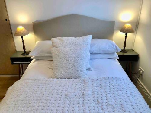 a bed with white blankets and pillows on it at A perfectly located bright, modern ,Victorian flat in Royal Tunbridge Wells