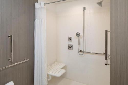 a white bathroom with a shower and a toilet at Courtyard by Marriott Detroit Farmington in Farmington Hills