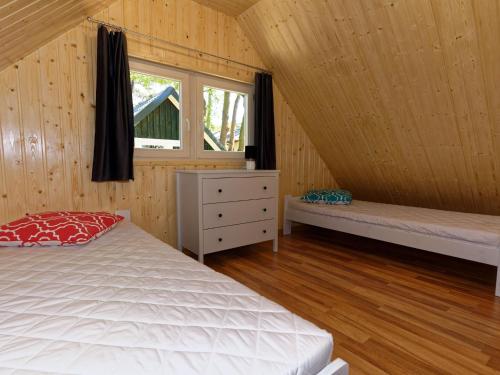 a bedroom with a bed and a window and wooden walls at Holiday house in Pobierowo for 4 people near the sea in Pobierowo