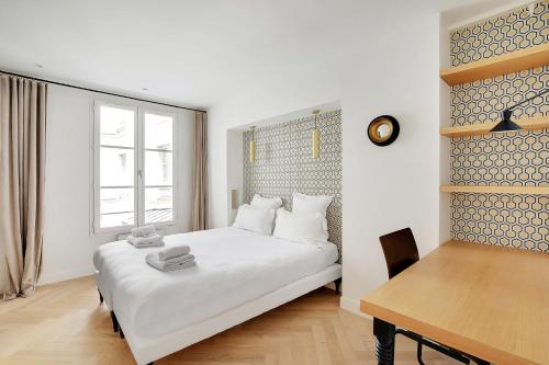 - une chambre avec un lit blanc et une table en bois dans l'établissement Pick A Flat's Apartment in Triangle d'Or - Rue Penthievre, à Paris