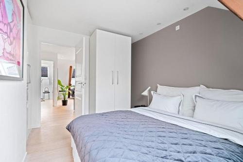 a bedroom with a large bed with white walls at Nydelig toppleilighet med terrasse midt i sentrum in Bergen