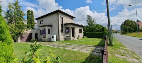 a white house with purple flowers in the yard at Elly House in Haapsalu