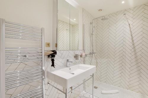une salle de bain blanche avec un lavabo et un miroir dans l'établissement Pick A Flat's Apartment in Triangle d'Or - Rue Penthievre, à Paris