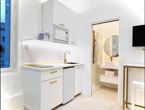 - une cuisine blanche avec un évier et un miroir dans l'établissement Cosy Suite - Élégance & Calme en Hyper-Centre, à Montpellier