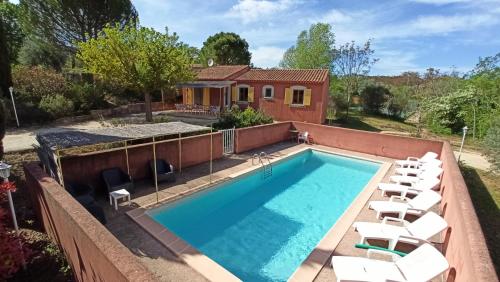 une piscine avec des chaises et une maison dans l'établissement La Bastide de la Peyrolière avec piscine et tennis face au Luberon, à Apt
