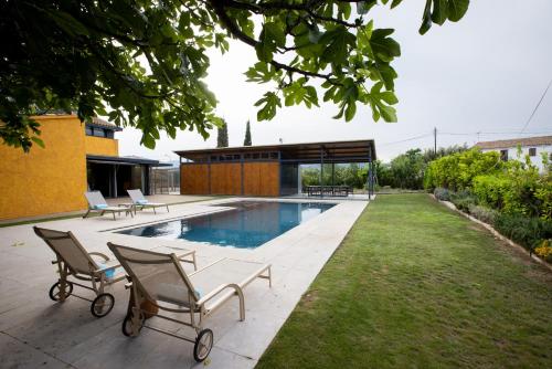 a backyard with a pool and two chairs and a table at Masia Cal Sisplau, con piscina y rodeada de viñedos a 10 minutos de Vilafranca del Penedés, Barcelona ,Cataluña in San Martín Sarroca