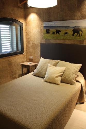 a bedroom with a bed with a painting on the wall at Masia Cal Sisplau, con piscina y rodeada de viñedos a 10 minutos de Vilafranca del Penedés, Barcelona ,Cataluña in San Martín Sarroca