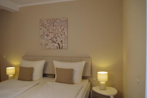 a bedroom with two beds and two lamps and a painting at Gast und Weinhof Beim Schneemann in Valwig