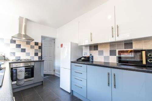 a kitchen with white cabinets and blue appliances at Warburton House, Newark - Walking distance from North Gate Train Station & Market Place in Newark upon Trent