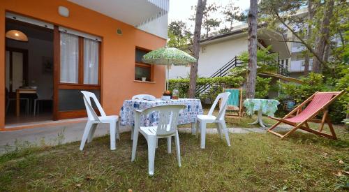 un tavolo con sedie e un ombrellone in un cortile di Villa Rosanna a Lignano Sabbiadoro