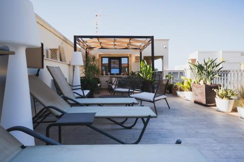 a patio with chairs and tables on a building at RIAD Comfort Rooms in San Vito lo Capo
