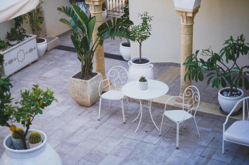 a patio with tables and chairs and potted plants at RIAD Comfort Rooms in San Vito lo Capo