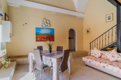 a dining room with a table and chairs and a couch at La rimesa di Tittì - Anna in Alezio
