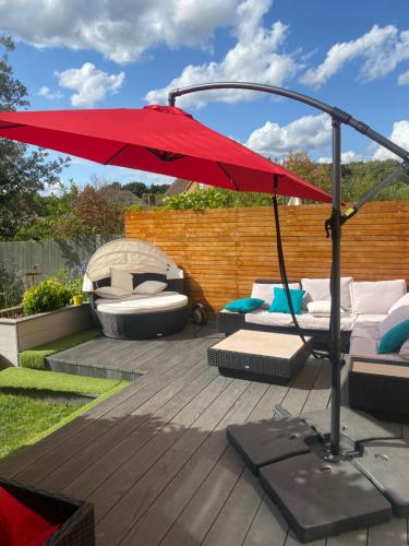 a red umbrella on top of a deck with beds and a grill at Two double bedrooms in Paddock Wood in Paddock Wood